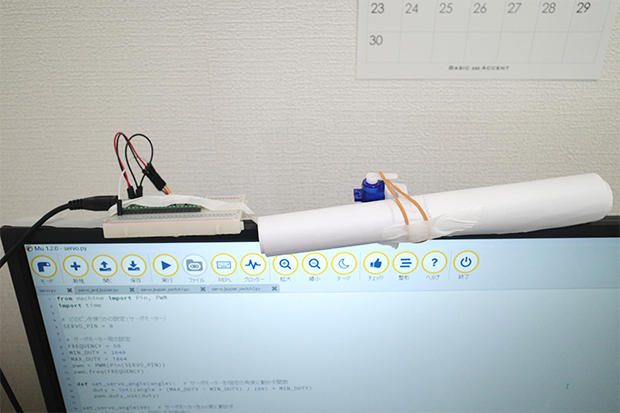 Mu Editor上で「実行」を押すと、サーボモーターに付いているストッパー（輪ゴム）が外れて垂れ幕が下りる仕組み。